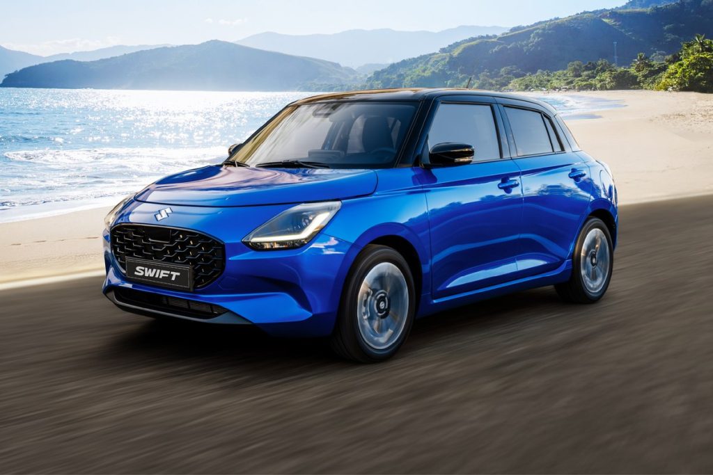 Suzuki Swift màu xanh chạy trên đường ven biển