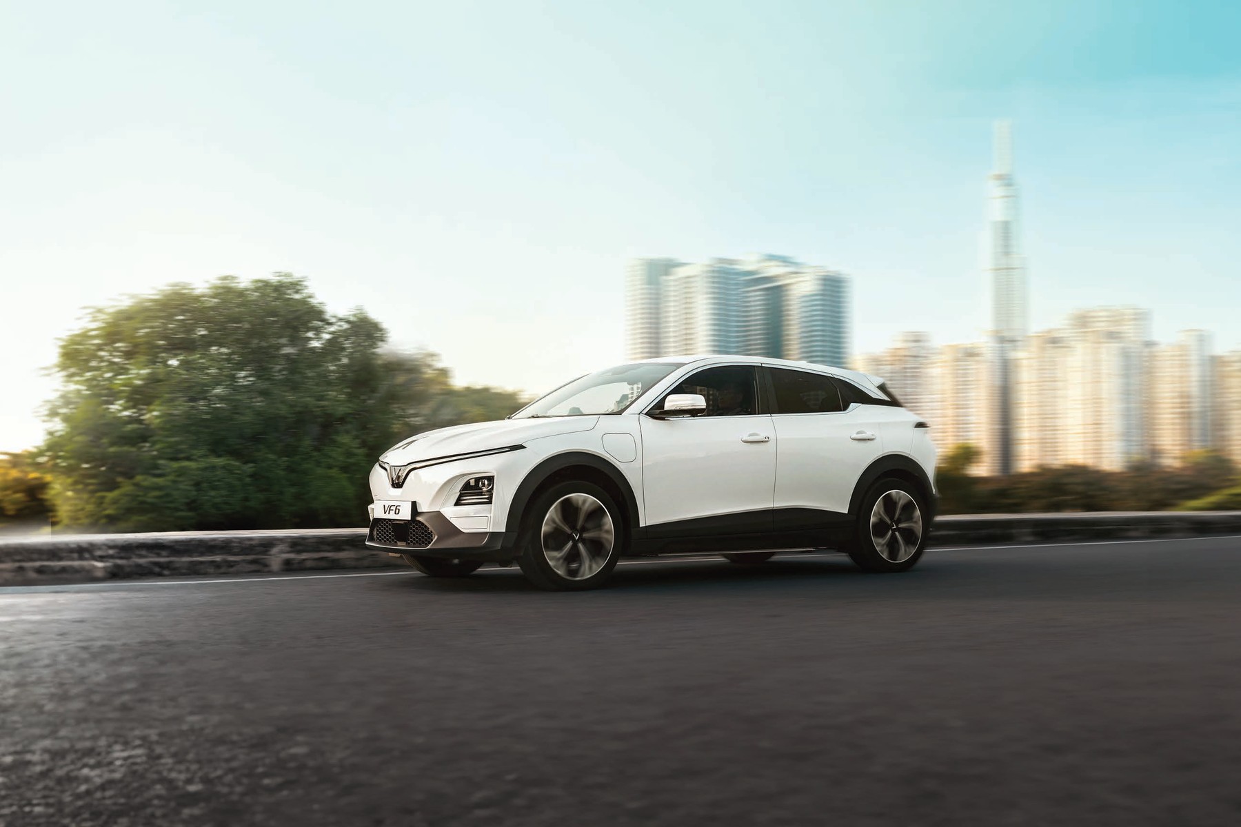 VinFast VF6 màu trắng nhìn từ góc 3/4 phía trước giữa khung cảnh đô thị