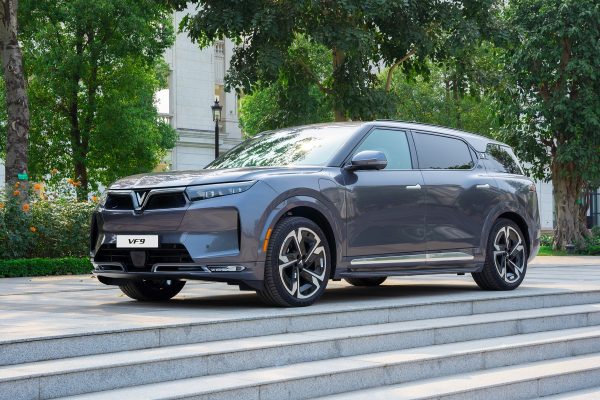 VinFast VF9 màu xám Neptune Grey đỗ trên bậc thềm đá, nhìn từ góc 3/4 phía trước