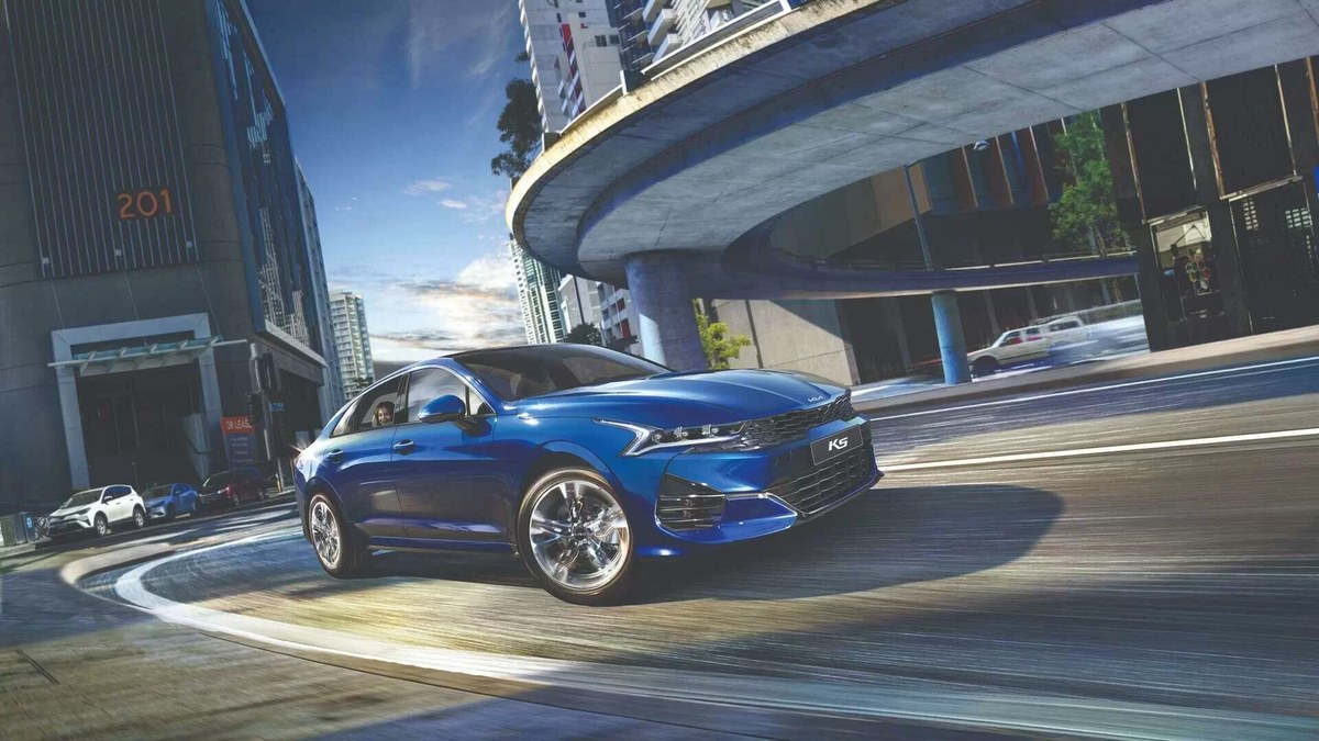 Kia K5 màu xanh chạy trên đường phố