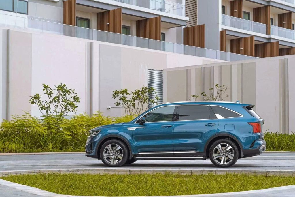 Sorento Plug-in Hybrid màu xanh chạy cạnh khu nhà ở